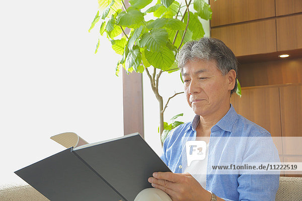 Modischer japanischer älterer Mann  der ein Buch liest