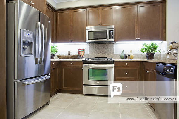 Küche mit braunen Schränken und Kühlschrank aus Edelstahl zu Hause