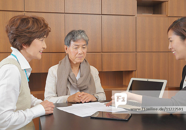Fashionable Japanese senior couple discussing with advisor