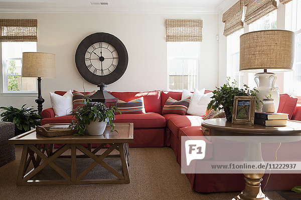 Modernes Wohnzimmer mit rotem Sektionssofa und großer Wanduhr zu Hause