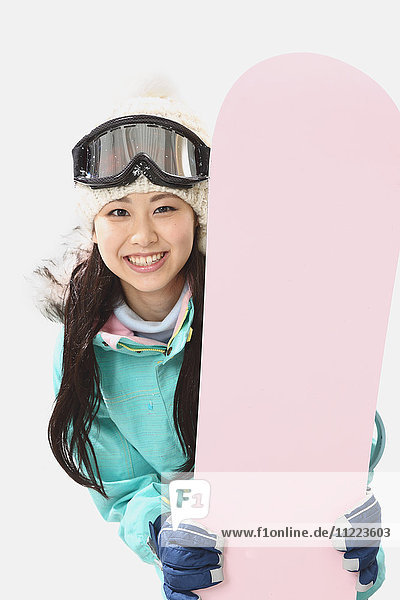 Junge japanische Frau in Snowboardkleidung auf weißem Hintergrund