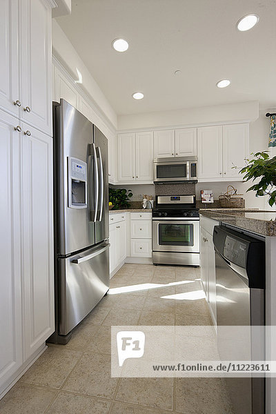 Küche mit weißen Schränken und Kühlschrank aus Edelstahl zu Hause