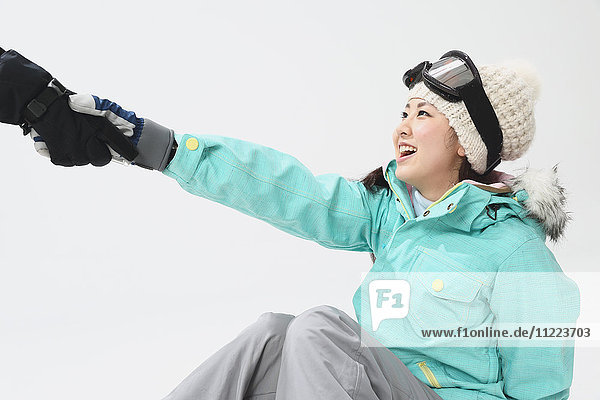 Junge japanische Frau in Snowboardkleidung auf weißem Hintergrund