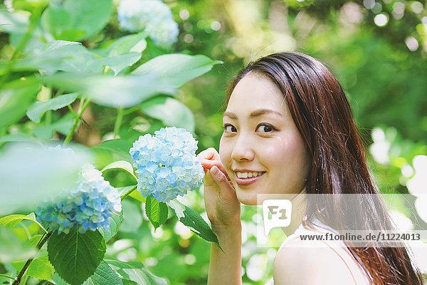 Junge Japanerin mit Hortensienblüten in einem Stadtpark