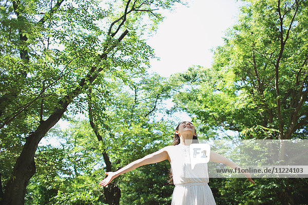 Junge japanische Frau umgeben von Grün in einem Stadtpark