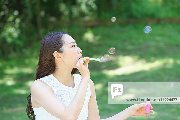 Junge Japanerin bläst Seifenblasen in einem Stadtpark