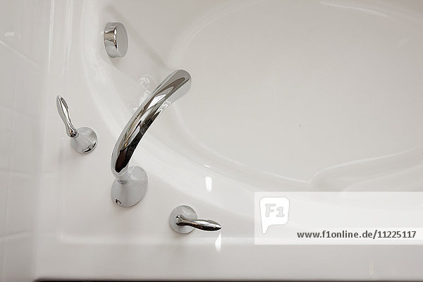 Close-up shot of faucet at cropped bathtub in the bathroom