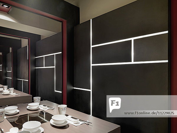 Schwarze Wand mit eingebauten Lichtern im asiatischen Esszimmer