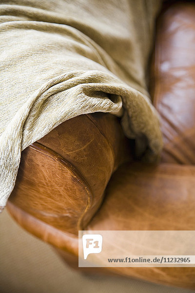 Detail einer Ledercouch mit Decke.