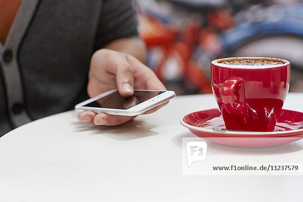 Person mit Smartphone und Kaffee