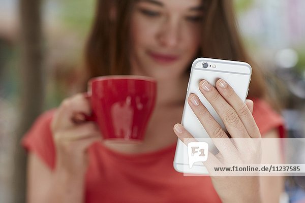 Frau mit Smartphone beim Kaffeetrinken
