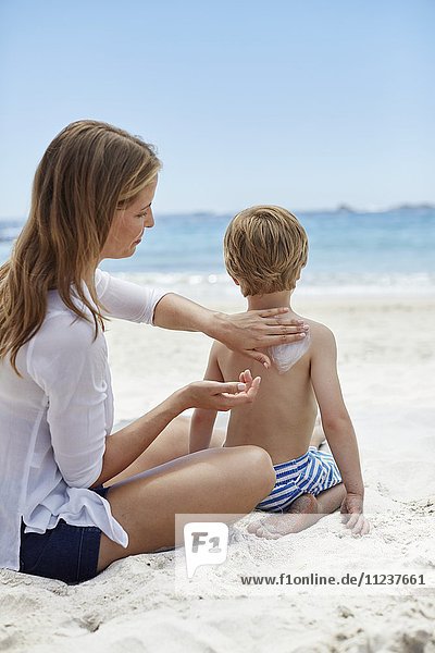 Mutter trägt ihrem Sohn Sonnencreme auf