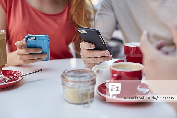 Junge Menschen im Café nutzen Smartphones