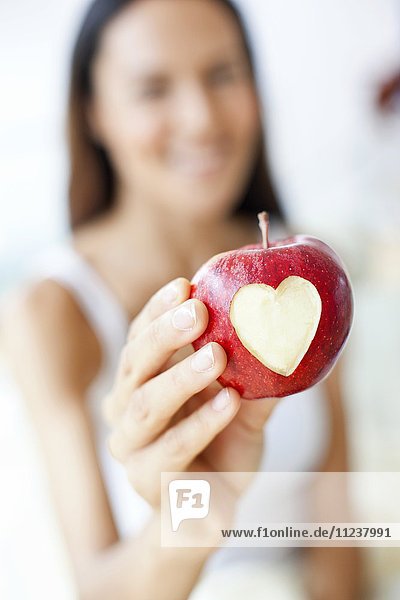 Young woman holding apple with heart
