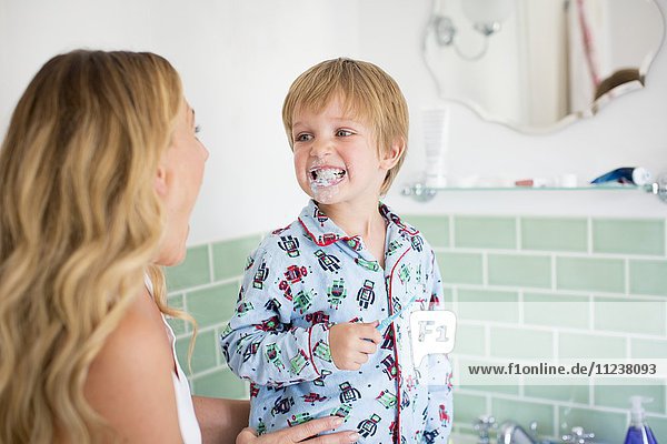 Mother and son in bathroom brushing teeth