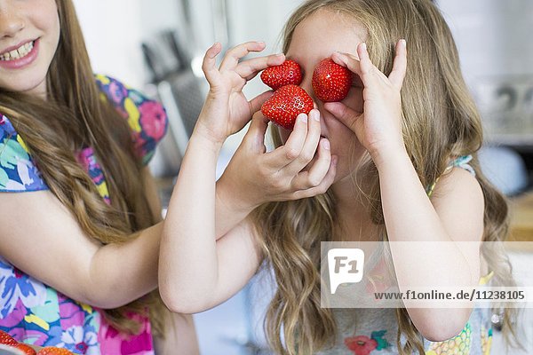 Girl with strawberries covering her eyes