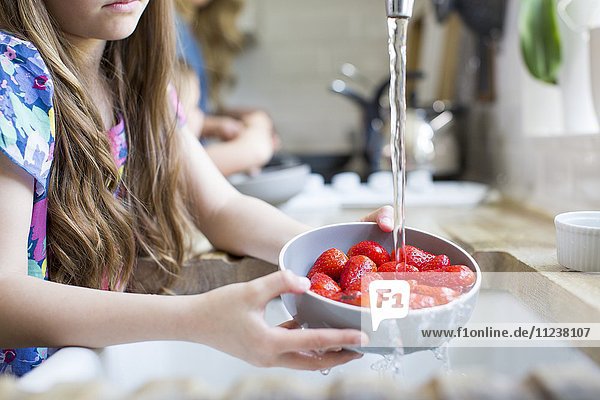 Mädchen wäscht frische Erdbeeren