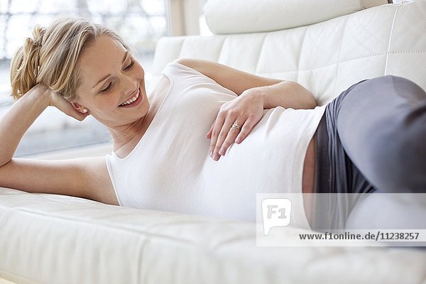 Schwangere Frau auf Sofa liegend