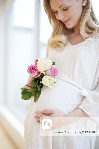 Schwangere Frau hält Blumenstrauß