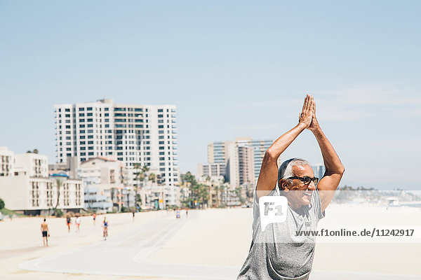 Senior man  exercising on beach  in yoga position  Long Beach  California  USA