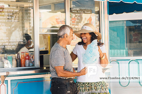Senior couple standing beside refreshment stand  holding cotton candy  Long Beach  California  USA