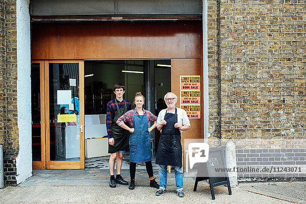 Family portrait of senior craftsman with daughter and son outside print workshop