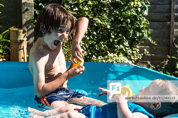 Glückliche Brüder spielen am Sommertag im aufblasbaren Pool