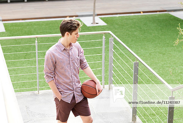 Junger Mann im Freien  hält Basketball