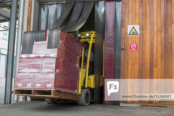 Gabelstaplerfahrer mit Paletten fährt durch die Tür einer Verpackungsfabrik