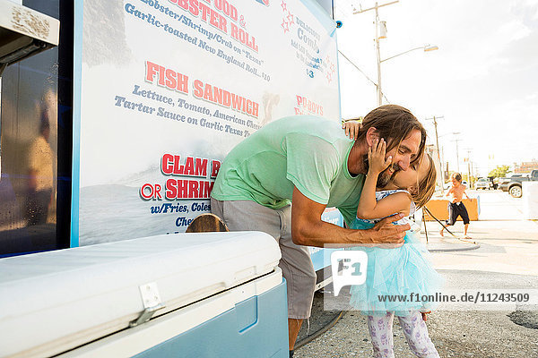 Vater und Tochter stehen neben Fastfood-Anhänger  Tochter küsst Vater