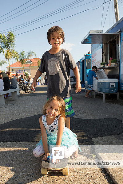 Porträt eines Jungen und Mädchens auf Skateboard
