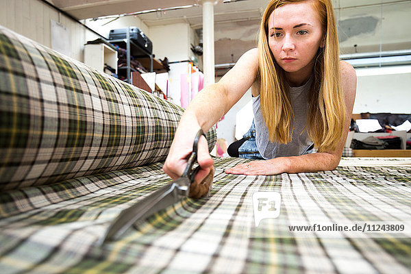 Young woman cutting fabric in leather jacket manufacturers