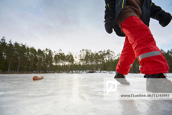 Blick von der Hüfte auf einen Jungen  der auf einem zugefrorenen See geht  Gavle  Schweden