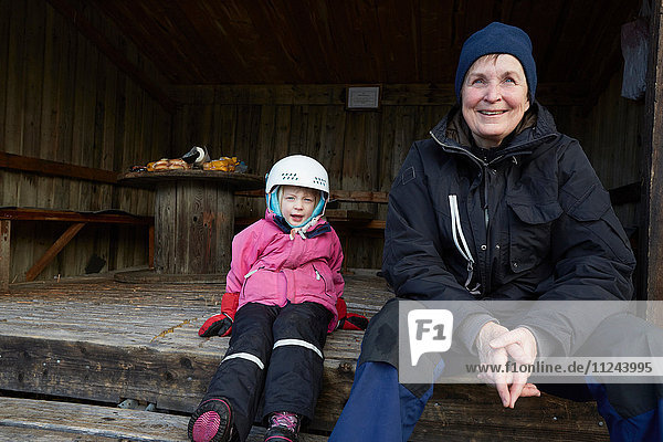 Mädchen mit Skihelm auf einer Scheunenstufe sitzend mit Grossmutter  Gavle  Schweden
