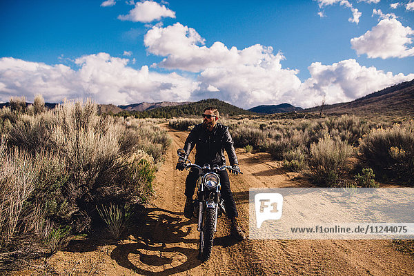 Motorradfahrer sitzt auf Motorrad und schaut weg  Kennedy Meadows  Kalifornien  USA