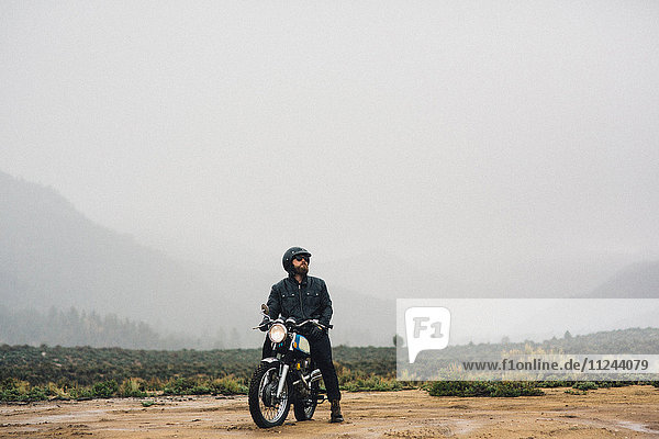 Motorcyclist wearing helmet sitting on motorbike looking away  Kennedy Meadows  California  USA
