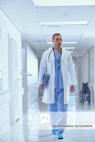 Arzt geht mit medizinischen Notizen den Krankenhauskorridor entlang