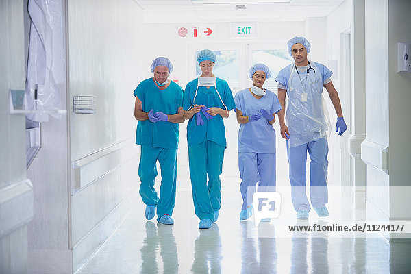 Four medical staff wearing scrubs walking in hospital corridor
