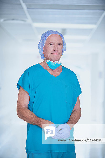 Portrait of senior male medic wearing scrubs in hospital corridor