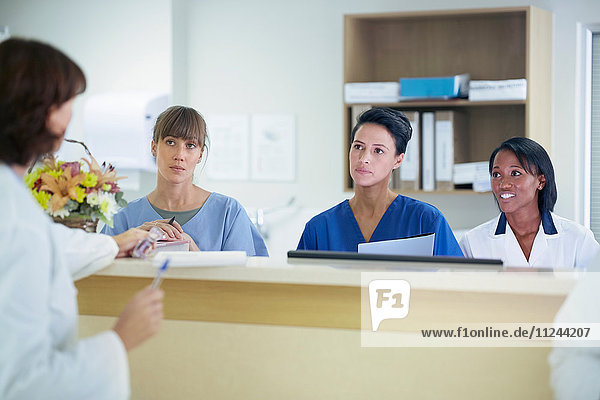 Ärztin im Gespräch mit Krankenschwestern auf der Krankenpflegestation im Krankenhaus
