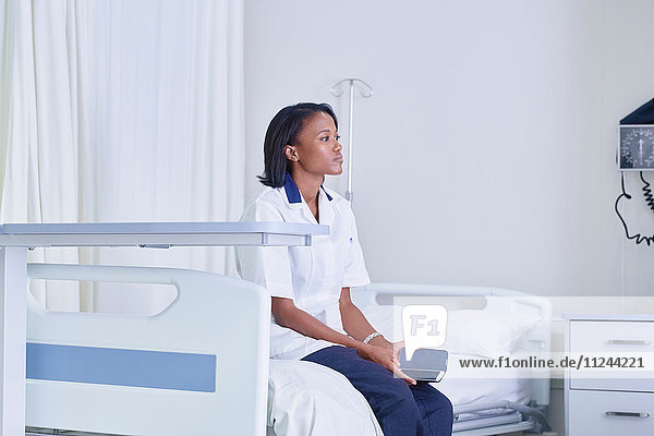 Female medic sitting gazing from hospital bed