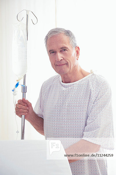 Porträt eines älteren männlichen Patienten mit intravenösem Tropf im Krankenhaus