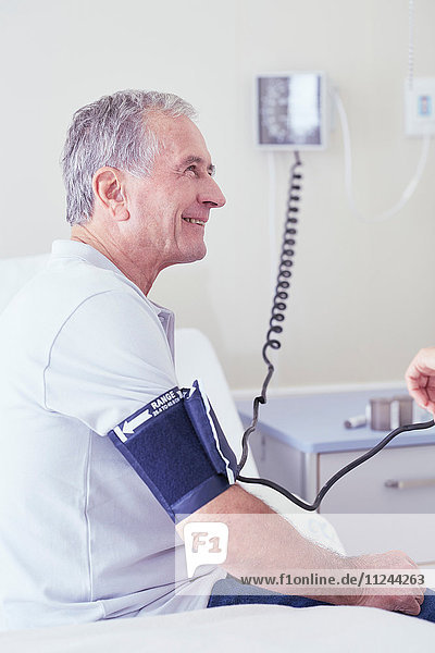 Älterer männlicher Patient  dessen Blutdruck vom Arzt gemessen wird