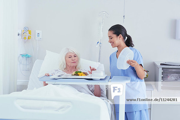 Krankenschwester serviert Mittagessen für ältere Patientin im Krankenhausbett
