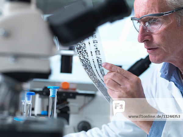 Forscher  der ein DNA-Gel während eines genetischen Experiments in einem Labor in der Hand hält