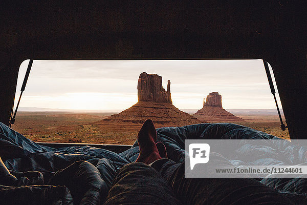 Male legs and feet relaxing inside four wheel drive with view of sandstone buttes from car boot  Monument Valley  Arizona  USA