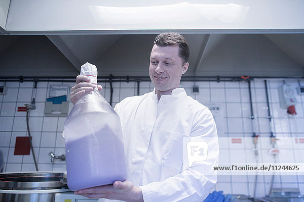 Wissenschaftler mit großer Flasche Chemikalie im Labor