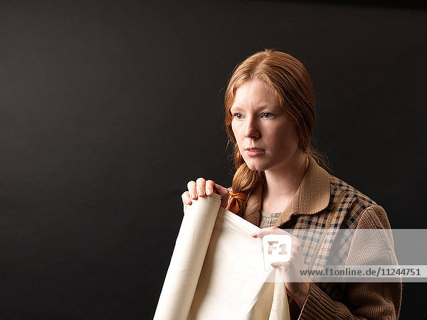 Portrait of young female designer holding rolled fabric