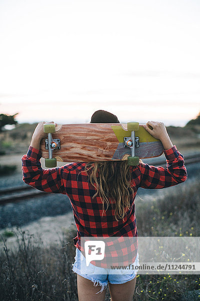 Woman with skateboard on shoulders