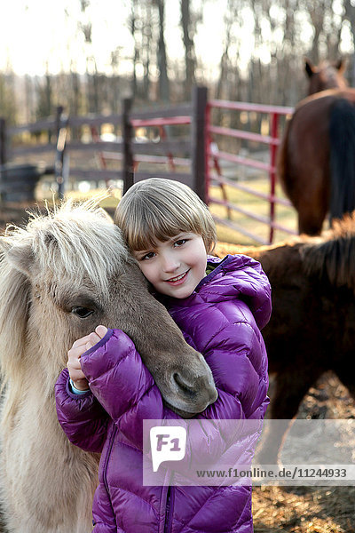 Porträt eines jungen Mädchens im Freien  das ein Pony umarmt